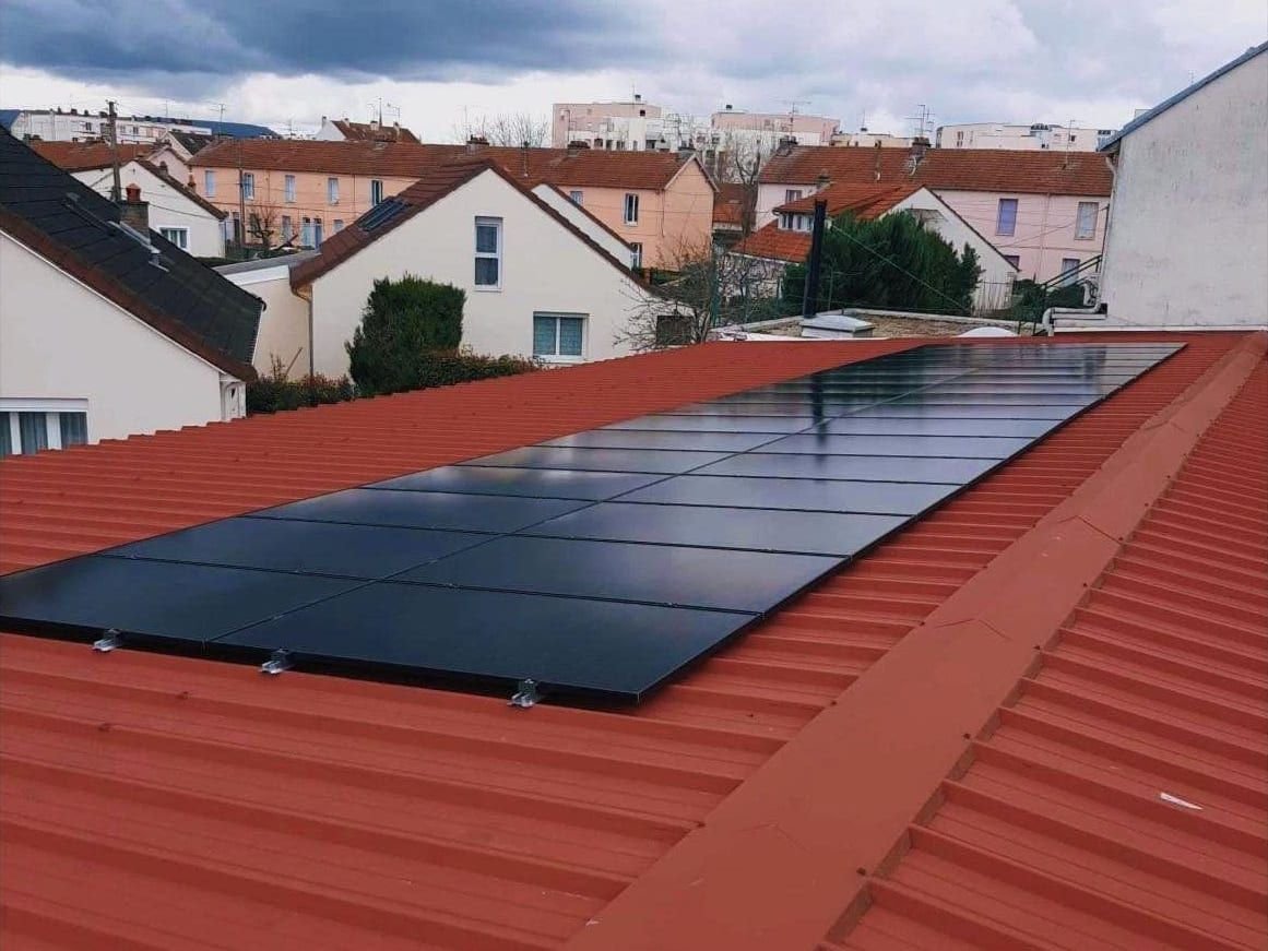 Panneaux solaires photovoltaïques noirs sur une toiture en bac acier rouge, en Seine-Maritime