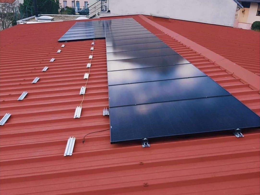 Pose de panneaux solaires photovoltaïques et de leurs fixations sur une toiture en bac acier rouge, en Seine-Maritime